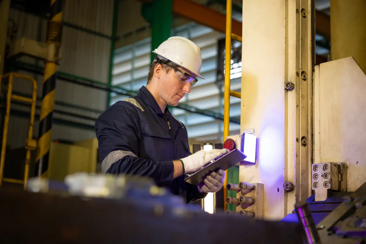 Técnico da Ativa inspecionando painel de máquina industrial com tablet
